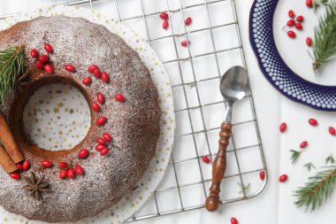 Kırmızı böğürtlenler ve beyaz arka planda köknar dallarıyla süslenmiş şenlikli kek..