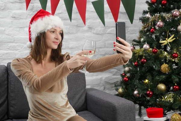 Young woman alone at home on video call celebrating Christmas or New Year Eve.