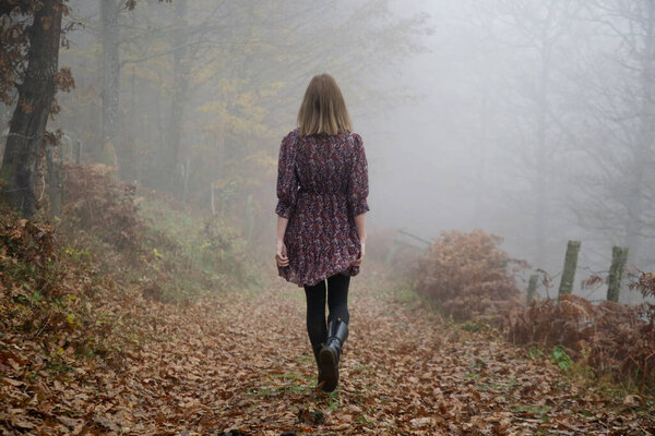 Outdoor portrait of woman in brown dress during foggy autumn morning in the countryside.