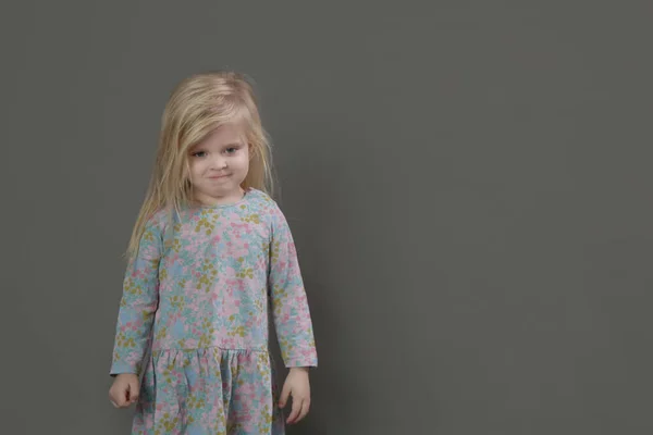 ファッションスタジオポートレートの可愛いです3歳ブロンド女の子で花パターンドレス上の灰色の背景 — ストック写真