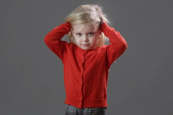 단추가 스웨터를 배경에 격자무늬 반바지를 귀여운 소녀의 스튜디오 — 스톡 사진