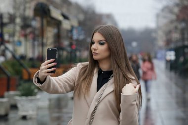 Yağmurlu bir günde şehirde deve kürkü giyen şık bir kadının açık hava portresi.