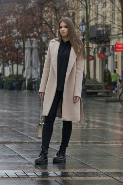 Yağmurlu bir günde şehirde deve kürkü giyen şık bir kadının açık hava portresi.