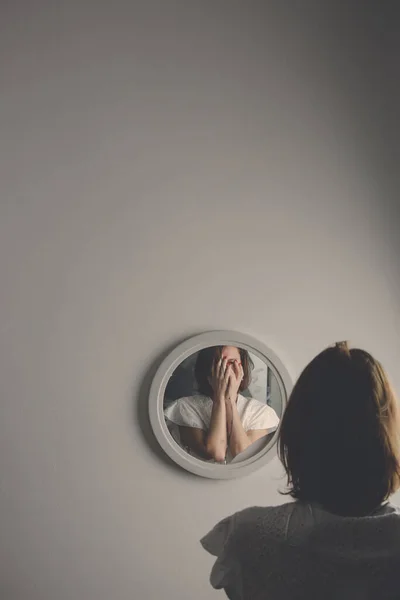 Reflection of a woman's face in broken mirror. Depression, anxiety, phobia, suicide and mental health concept.