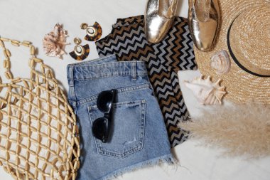 Basit yaz kıyafeti, kot şort ve beyaz arka planda aksesuarları olan kahverengi gömlek. Kadınların günlük moda eşyaları, üst görünüm..