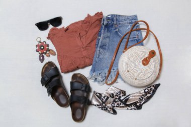 Basit bir yaz kıyafeti, kot şortu ve beyaz arka planda aksesuarları olan keten bir gömlek. Kadınların günlük moda eşyaları, üst görünüm..