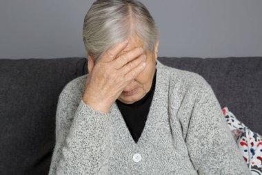 Yüzü elleri, depresyonu, üzüntüyü, kederi ya da baş ağrısı konseptiyle örten yaşlı kadın görüntüsü. 