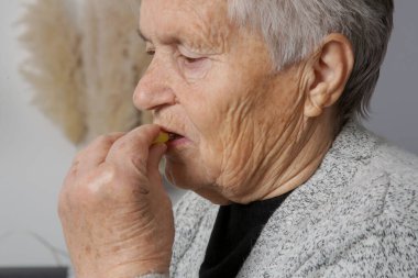 Evde hap alan yaşlı bir kadın.