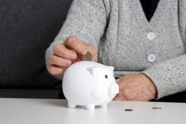 Yaşlı kadın kumbaradaki son paraları sayıyor, depresif ve endişeli bir şekilde evde oturuyor. Tasarruf, sigorta ve emeklilik kavramı.