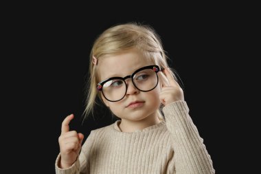 Okuma gözlüğü takan küçük sevimli bir kızın stüdyo portresi.