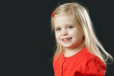 Kırmızı hırkalı güzel sarışın küçük kızın stüdyo portresi.