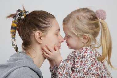 Annesini öpen tatlı bir kızın stüdyo portresi.