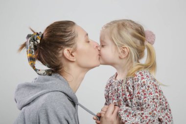 Annesini öpen tatlı bir kızın stüdyo portresi.
