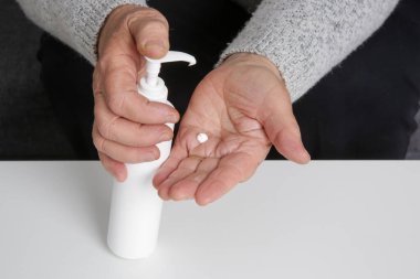 Kollarına nemlendirici losyon süren çok kuru ciltli yaşlı bir kadın.