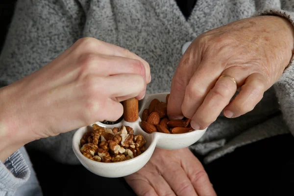 Senior woman having nuts and dried fruits for snack. Healthy dieting and smart snack choice.