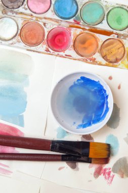 Suluboya palet, fırça ve kağıtları masaya koyar. Yaratıcı hobi ya da sanat terapisi kavramı.