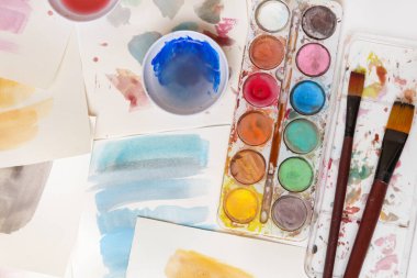 Suluboya palet, fırça ve kağıtları masaya koyar. Yaratıcı hobi ya da sanat terapisi kavramı.