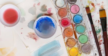 Suluboya palet, fırça ve kağıtları masaya koyar. Yaratıcı hobi ya da sanat terapisi kavramı.