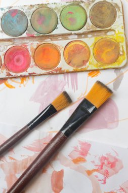 Suluboya palet, fırça ve kağıtları masaya koyar. Yaratıcı hobi ya da sanat terapisi kavramı.