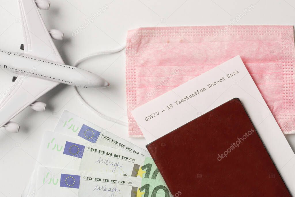 Travelling during corona virus epidemic, COVID-19 vaccination record card, passport, money and medical mask on white background.