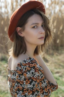 Açık hava portresi. Siyah çiçekli ve turuncu şapkalı genç bir kadın. Sıradan yaz modası..