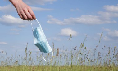  Coronavirus bitti. Karantina ve Corona Virüsü salgınının sonu. Kadın kalkıyor ve tıbbi koruyucu maskeyi atıyor. Coronavirüs salgınından sonra hayatın ve temiz havanın tadını çıkarıyorum..