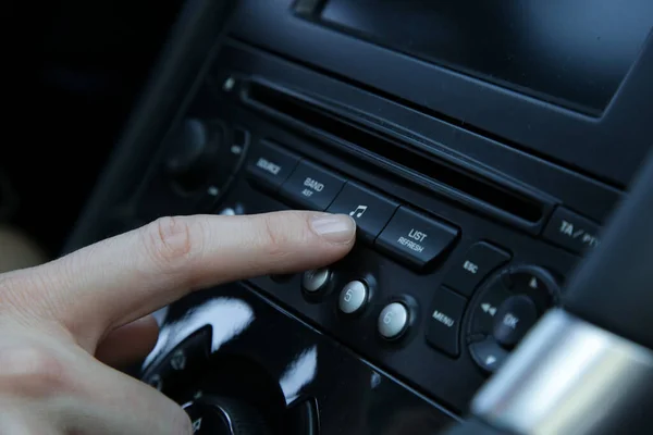 Woman set up music in car. Car dashboard close up