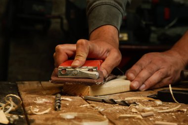 Marangoz atölyedeki bir tahta parçası üzerinde zımpara kağıdı kullanıyor. Kum tahtası..