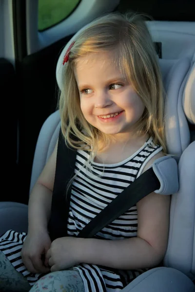 可爱的小女孩把安全带系在安全的汽车座椅上 — 图库照片