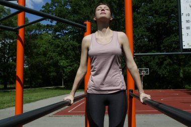 Açık hava eğitim sahasında barlarda dalış yapan sağlıklı genç bir kadın.