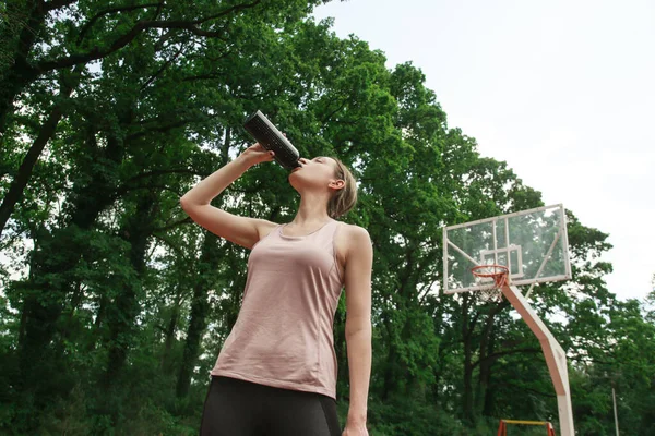 スポーツ場の外でワークアウト後の美しい女性のフィットネスモデル飲料水 — ストック写真