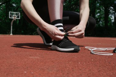 Koşu ayakkabıları. Spor sahasında ayakkabı bağı bağlayan bir kadın. Koşucu koşuya hazırlanıyor.