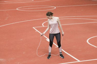 Spor sahasında ip atlayan genç bir kadın.