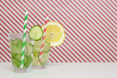 Lemon cucumber water with colorful paper straw. Healthy detox drink. clipart