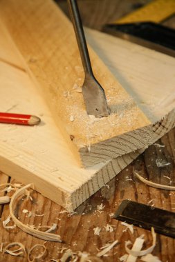 Marangoz atölyedeki tahtaya matkapla delik açıyor.