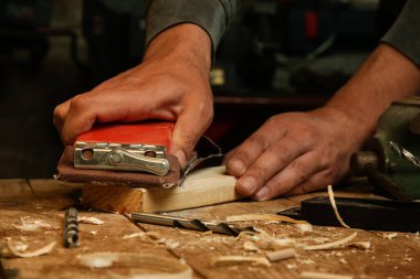 Marangoz atölyedeki bir tahta parçası üzerinde zımpara kağıdı kullanıyor. Kum tahtası..