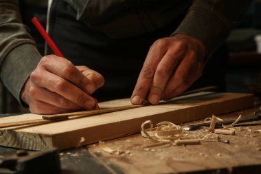 Marangoz atölyede odun ölçüyor ve işaretliyor
