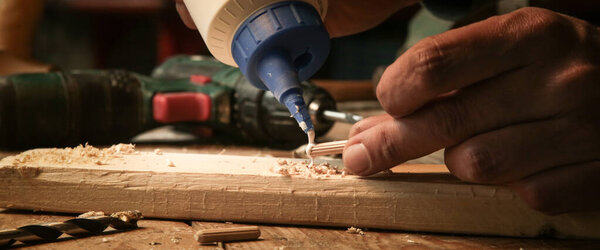 Handyman assembling wooden pieces with a glue