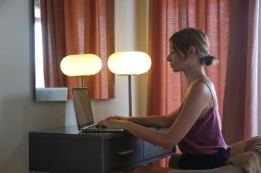 Genç yazar, blogcu, serbest çalışan ya da masada oturup dizüstü bilgisayar üzerinde çalışan öğrencinin kapalı portresi