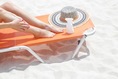 Bacaklarına güneş kremi süren bir kadın. Güneş koruma cildi konsepti.