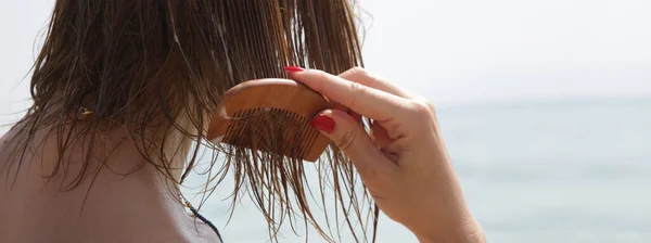 ビーチで女性の髪 木製の櫛で髪のマスクを再生女性 塩辛い海の水と太陽 夏のヘアケアの概念による髪の損傷 — ストック写真