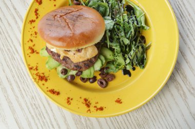 Yanında roka ve zeytinli hamburger.