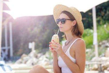 Plaj barında kokteyl içen genç bir kadın. İdilik yaz tatili konsepti.