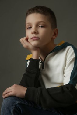 Gri arka planda yakışıklı okul çocuğunun stüdyo portresi..