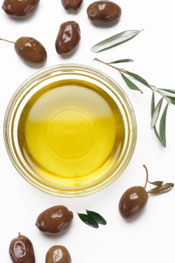 Ekstra saf zeytinyağının beyaz arka planda izole edilmiş kâse ve zeytinlerin üst görüntüsü.