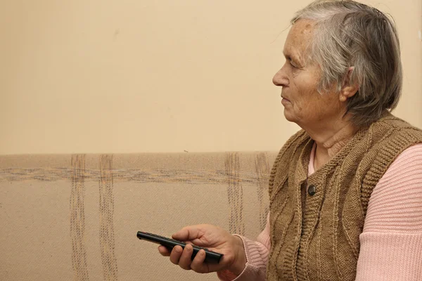 Elderly lady with remote control — Stock Photo, Image