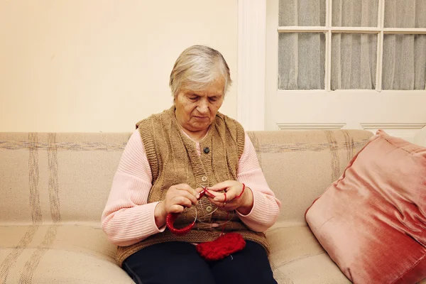 Elderly woman knitting with red wool — Stock Photo, Image