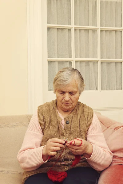 Oudere vrouw breien met rode wol — Stockfoto