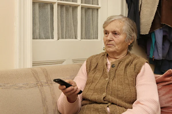 Elderly lady with remote control — Stock Photo, Image