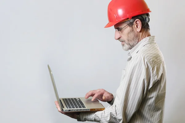 Retrato de um engenheiro com capacete e laptop, tiro estúdio — Fotografia de Stock